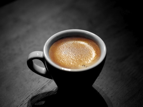 Espresso pour from a portafilter into a small white cup